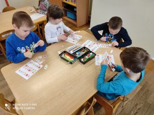 MISIAKI - Dzieci rozwiązujące przy stoliku diagram gry logicznej sudoku z figurami geometrycznymi