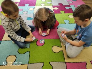 MISIAKI - Dzieci grające na dywanie w Dobble z kolorowymi kołami