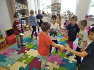 Bystrzaki - Grupa dzieci tańczy w sali - na pierwszym planie kilkoro chłopców tańczy wspólnie w kółku, na drugi planie pozostałe dzieci tańczą indywidualnie. 