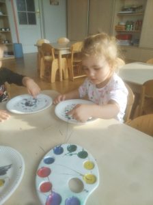 Krasnoludki -Chłopiec i dziewczynka siedzą przy stoliku i malują palcami